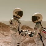 Two astronauts in full spacesuits holding hands in a barren, desert-like landscape symbolizing space exploration.
